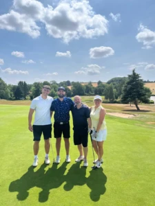 4 people posing for a photo on a golf course